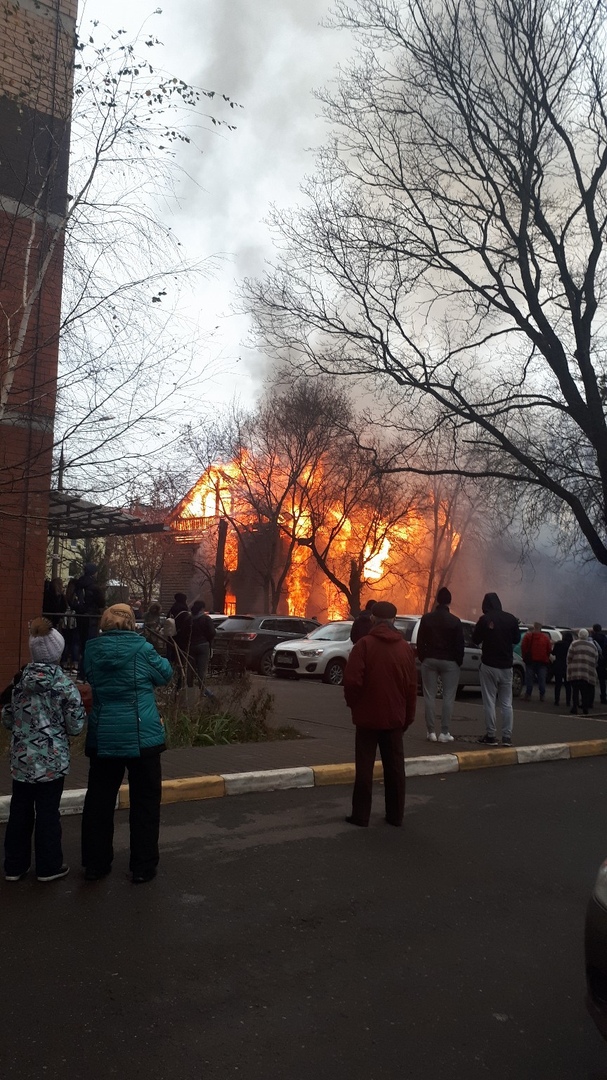 В Раменском горит дом, очевидцы отталкивают от него припаркованные автомобили.